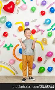 boy on a white background with colorful balloons. boy raising his hands up on a white background with balloons. boy in the background of balls