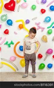 boy on a white background with colorful balloons. boy in a tank top and pants on a white background with balloons in the shape of a heart. boy in the background of balls