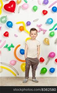 boy on a white background with colorful balloons. boy in a tank top and pants on a white background with balloons in the shape of a heart. boy in the background of balls