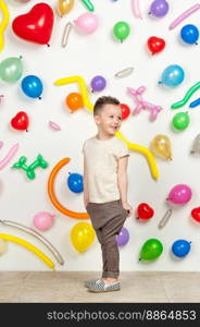 boy on a white background with colorful balloons. boy in a tank top and pants on a white background with balloons in the shape of a heart. boy in the background of balls