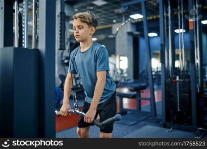 Boy on exercise machine, active training in gym. Youngster in sport club, healthcare and healthy lifestyle, schoolboy on workout, sportive youth. Boy on exercise machine, active training in gym