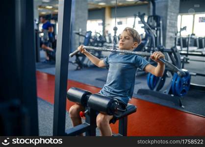 Boy on exercise machine, training in gym. Youngster in sport club, healthcare and healthy lifestyle, schoolboy on workout, sportive youth. Boy on exercise machine, training in gym