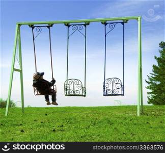 Boy on swing in back on blue sky