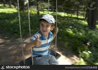 Boy on swing in forest. Swinging in forest