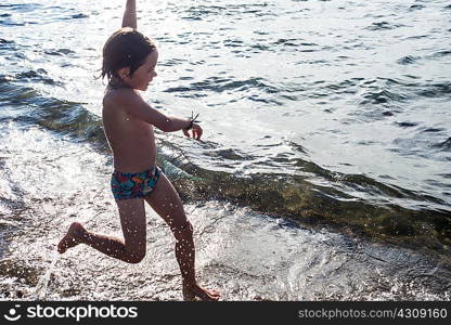 Boy paddling in lapping waves on coastline