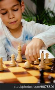 Boy playing chess at home. Sitting at the table and thinking hard.