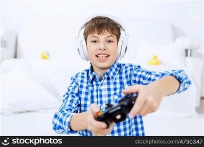 Boy playing game console. Emotional kid boy sitting on floor playing games on joystick