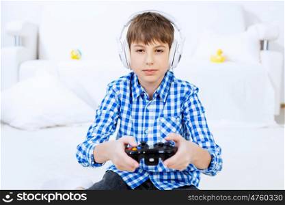 Boy playing game console. Emotional kid boy sitting on floor playing games on joystick