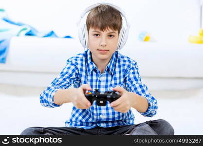 Boy playing game console. Emotional kid boy sitting on floor playing games on joystick