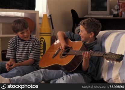 Boy Playing Guitar For Friend And Laughing