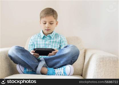 Boy playing hand-held video game on sofa