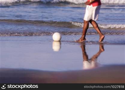 Boy playing soccer on the beach