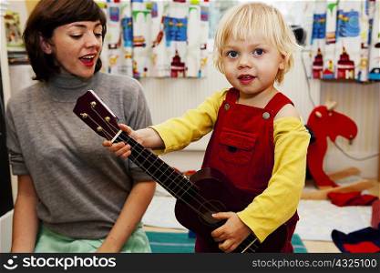 Boy playing toy guitar for mother