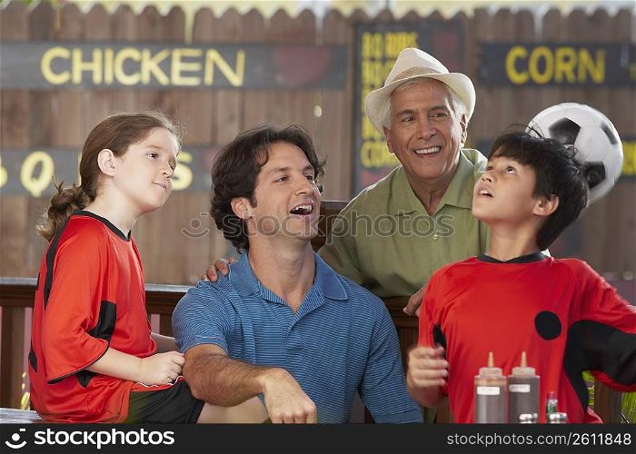 Boy playing with a soccer ball with her family sitting in a restaurant