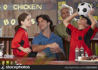 Boy playing with a soccer ball with his family beside him in a restaurant