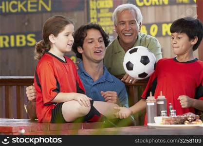 Boy playing with a soccer ball with his family beside him in a restaurant