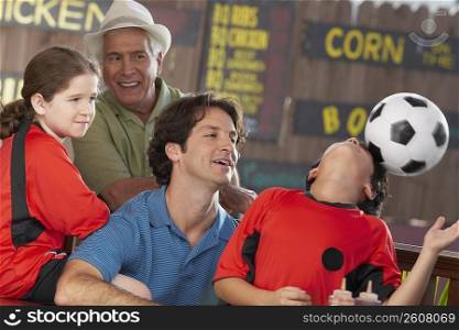 Boy playing with a soccer ball with his family looking at him in a restaurant
