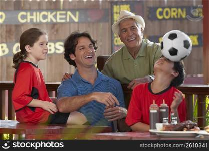 Boy playing with a soccer ball with his family looking at him in a restaurant