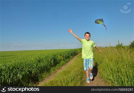 boy playing with kite on greenfield