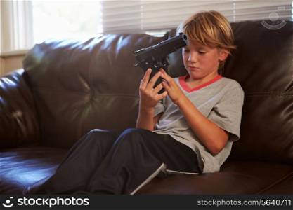 Boy Playing With Parent&#39;s Gun He Has Found At Home
