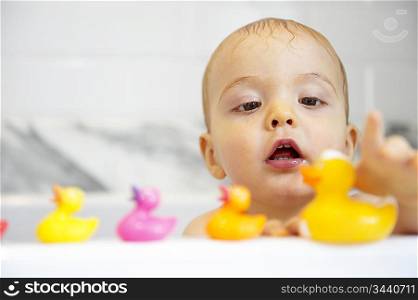 Boy playing with plastic ducks in bath