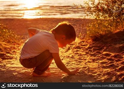 boy playing with sand on the beach. sunset
