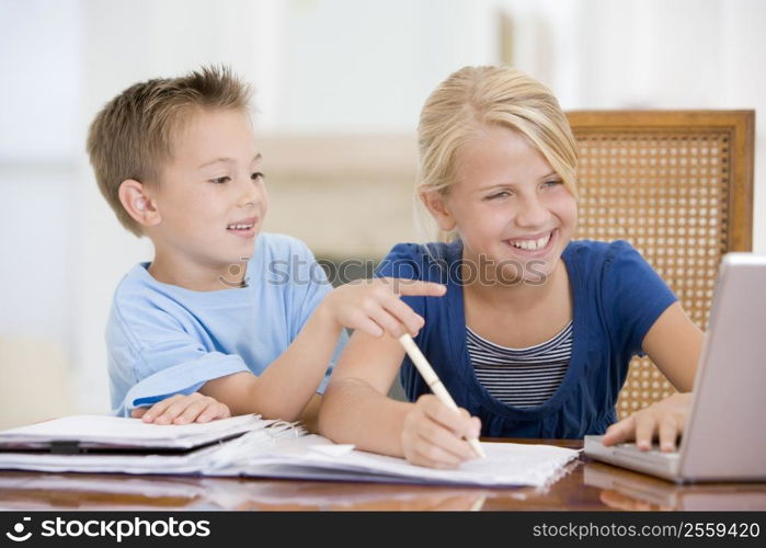 Boy Pointing At Big Sisters Homework On Laptop