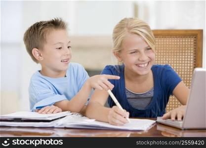 Boy Pointing At Big Sisters Homework On Laptop