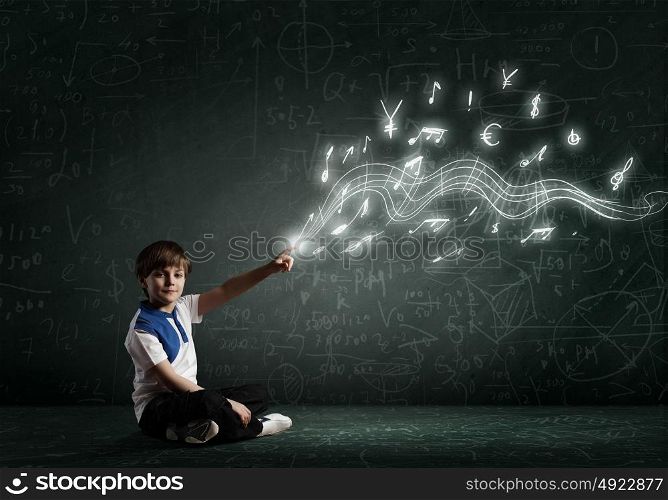 Boy pointing idea. Cute school boy sitting on floor and pointing with finger