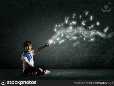 Boy pointing idea. Cute school boy sitting on floor and pointing with finger