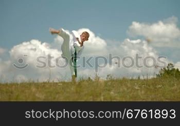 boy practicing karate on the nature against the sky on a sunny day