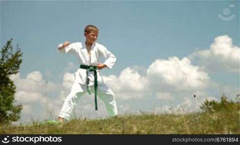boy practicing karate on the nature against the sky on a sunny day