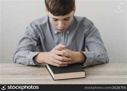 boy praying with his hands bible