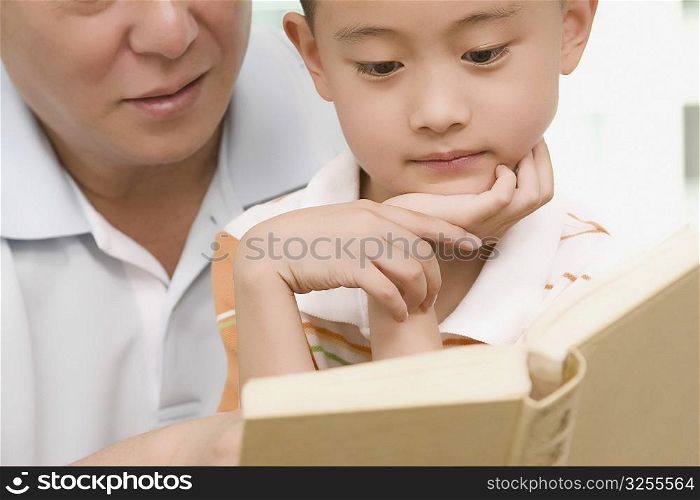 Boy reading a book with his grandfather