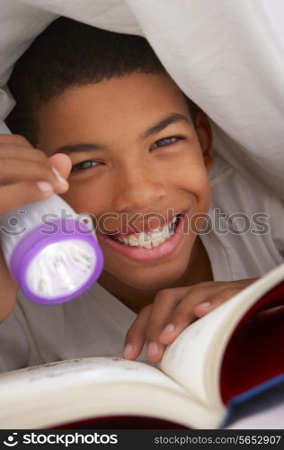 Boy Reading Book With Torch Under Duvet