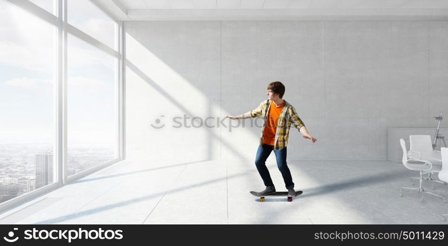 Boy ride skateboard. Active guy riding skateboard in office interior. Mixed media