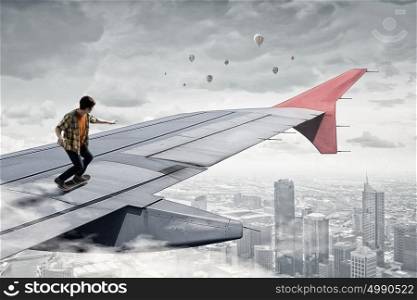 Boy ride skateboard. Active guy riding skateboard on airplane wing