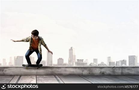 Boy ride skateboard. Active guy riding skateboard on building roof