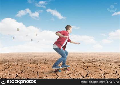 Boy ride skateboard. Active teenager guy riding skateboard in desert
