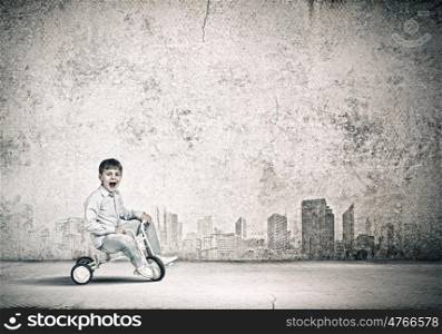 Boy riding bicycle. Little joyful cute boy riding tricycle on road