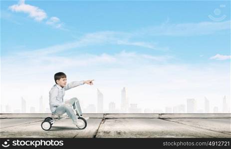 Boy riding bicycle. Little joyful cute boy riding tricycle on road
