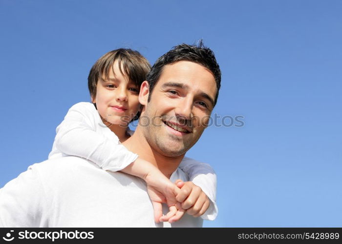 Boy riding piggy back on his father&rsquo;s back
