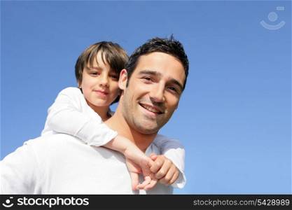 Boy riding piggy back on his father&rsquo;s back