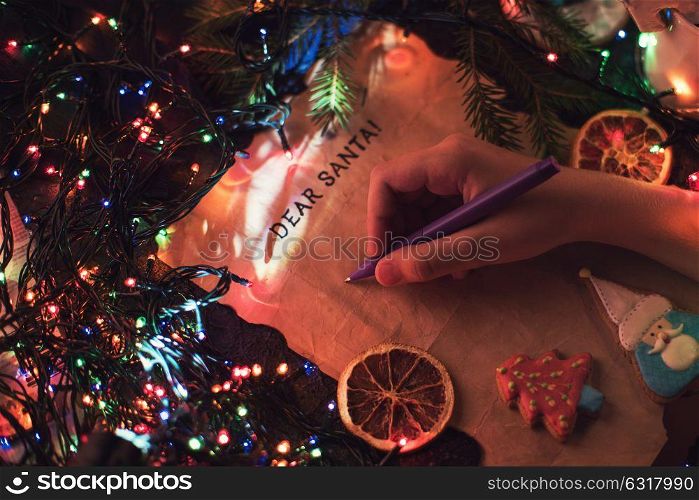 Boy&rsquo;s hand closeup, writing a letter to Santa, cristmas background. Letter to Santa