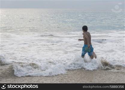 Boy running in waves on beach, Ixtapa, Guerrero, Mexico