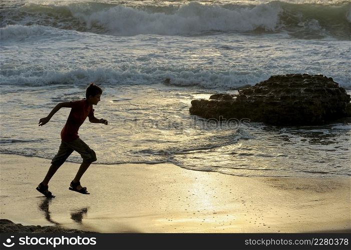 Boy runs along the shore of the Mediterranean Sea in Israel. Boy runs along the seashore