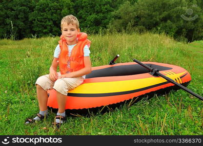 boy sits on an inflatable boat on lawn