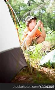 Boy sitting by tent at campsite