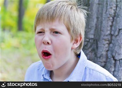 Boy sitting near tree and eating dessert with appetite