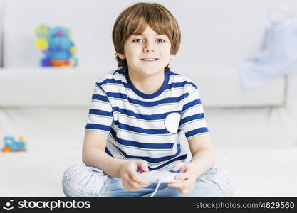 Boy sitting on floor and palying with joystick. I like video games